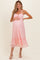 woman wearing a pink lace maternity dress with a fitted bodice and tiered skirt, holding her baby bump