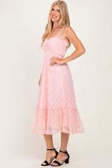 woman wearing a pink lace midi dress with smocked bodice and ruffled hem, standing with hand on hip