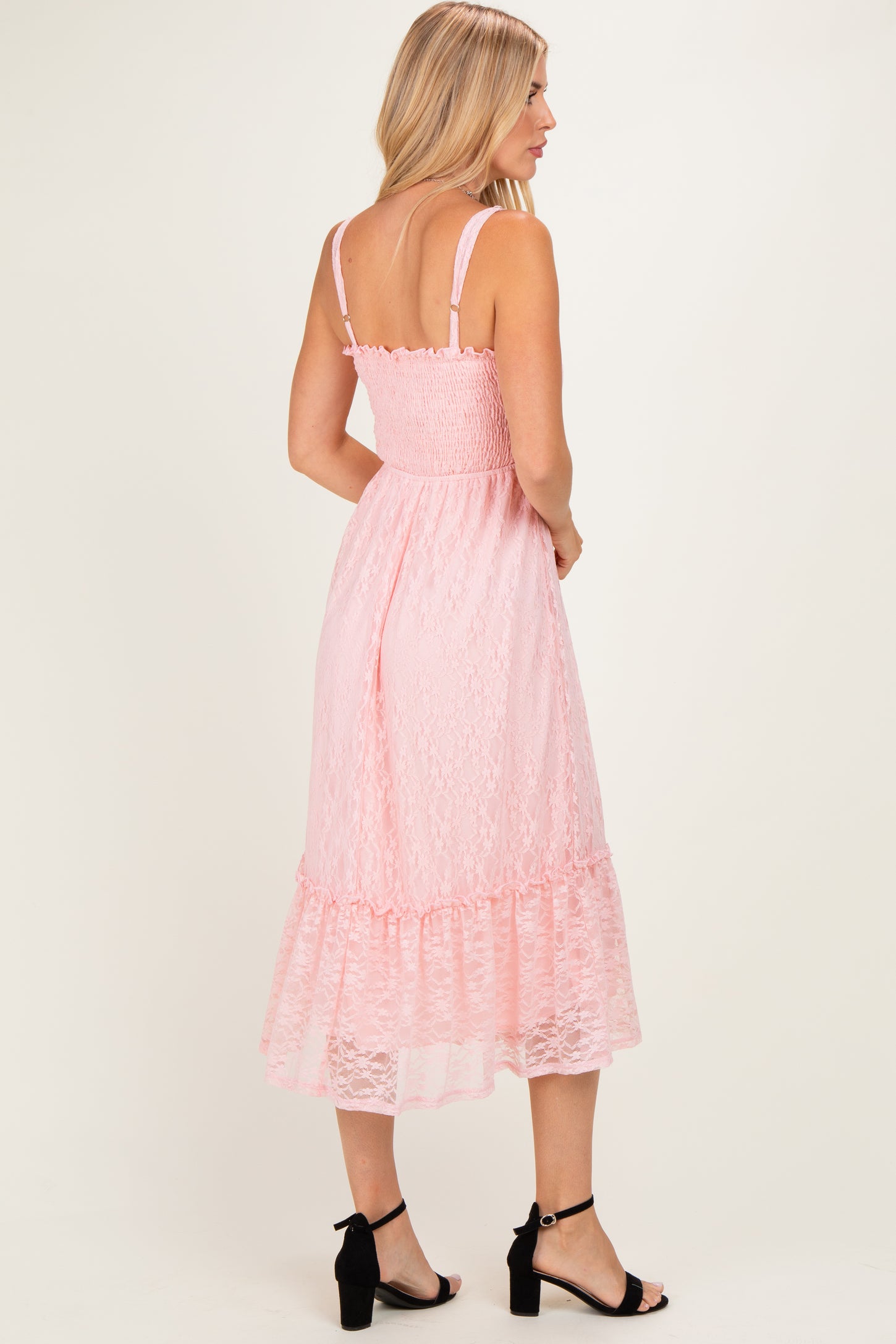 woman wearing a pink lace midi dress with a smocked bodice and ruffled hem, viewed from the back