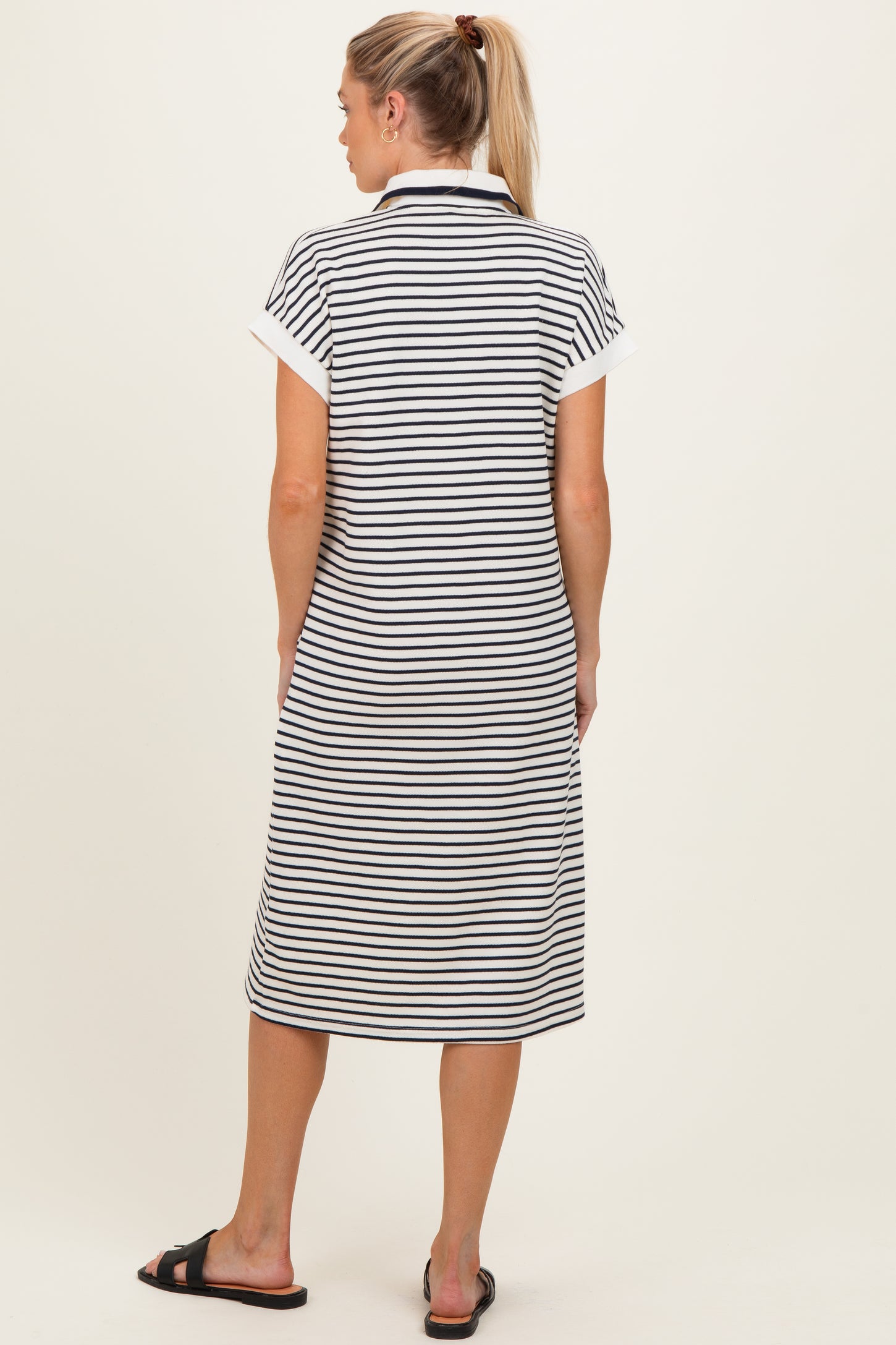 woman wearing a black and white striped maternity dress with short sleeves, shown from the back