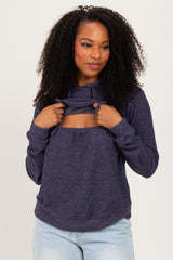 woman wearing a dark blue long sleeve hoodie with a cutout detail and adjusting the neckline