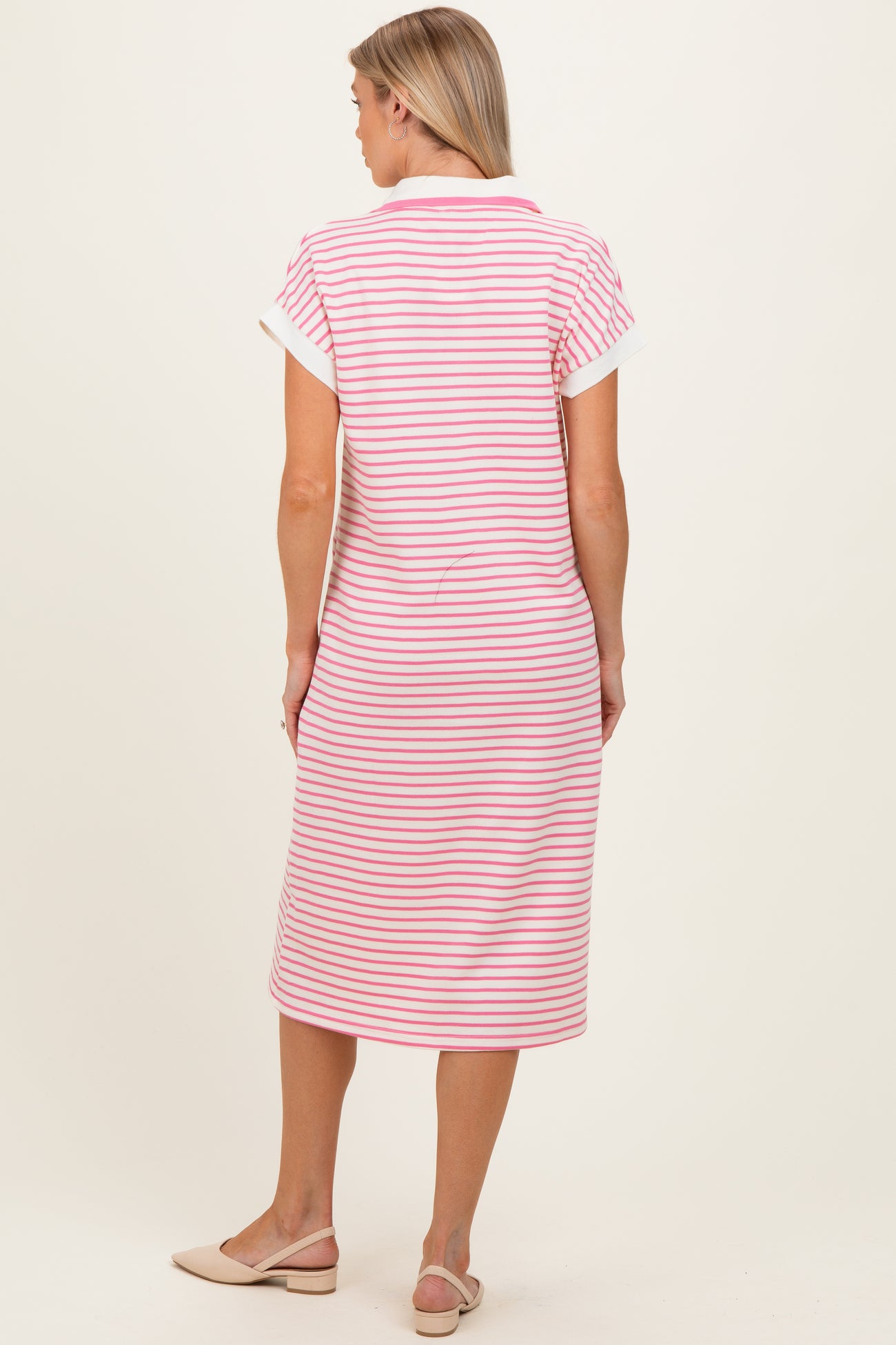 woman wearing a pink and white striped maternity dress with short sleeves, viewed from the back