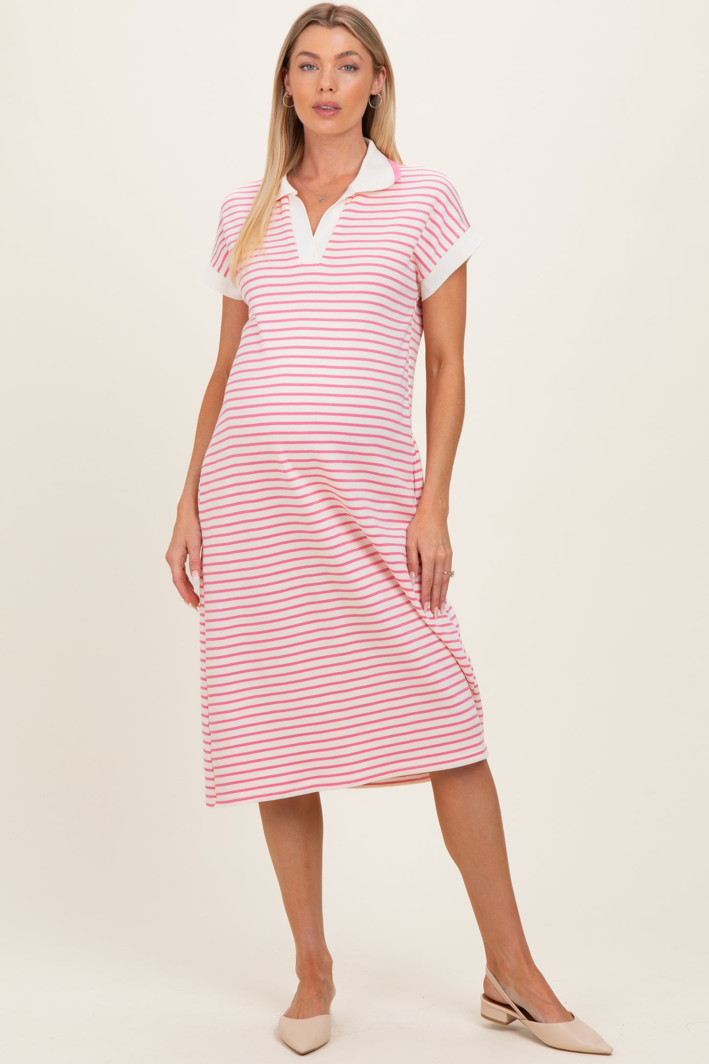 woman wearing a pink and white striped short sleeve maternity polo dress with a collar and a baby bump visible