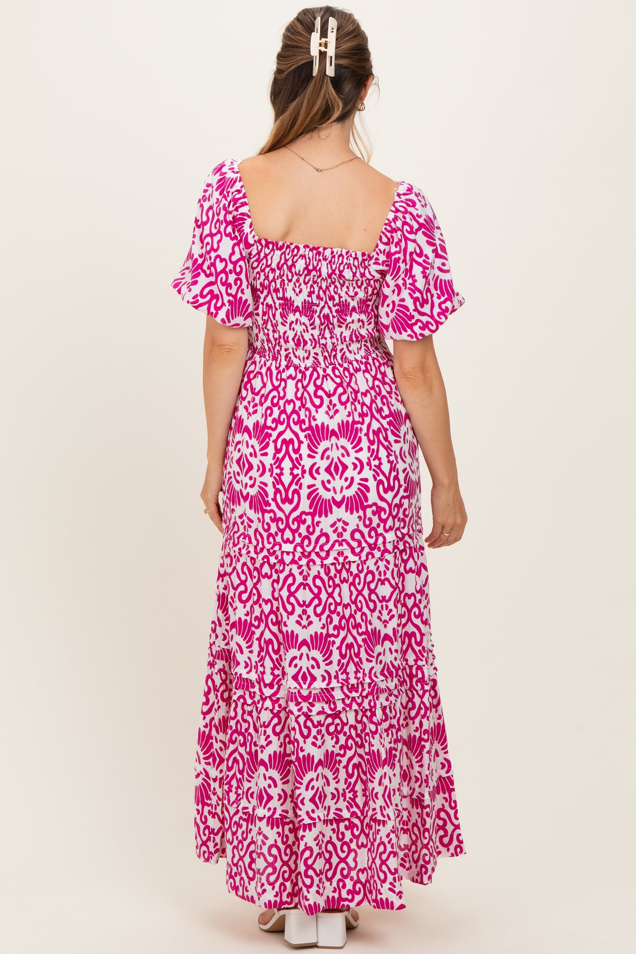 woman wearing a pink and white floral print maternity maxi dress with puff sleeves and a smocked back