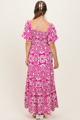 woman wearing a pink and white floral print maternity maxi dress with puff sleeves and a smocked back