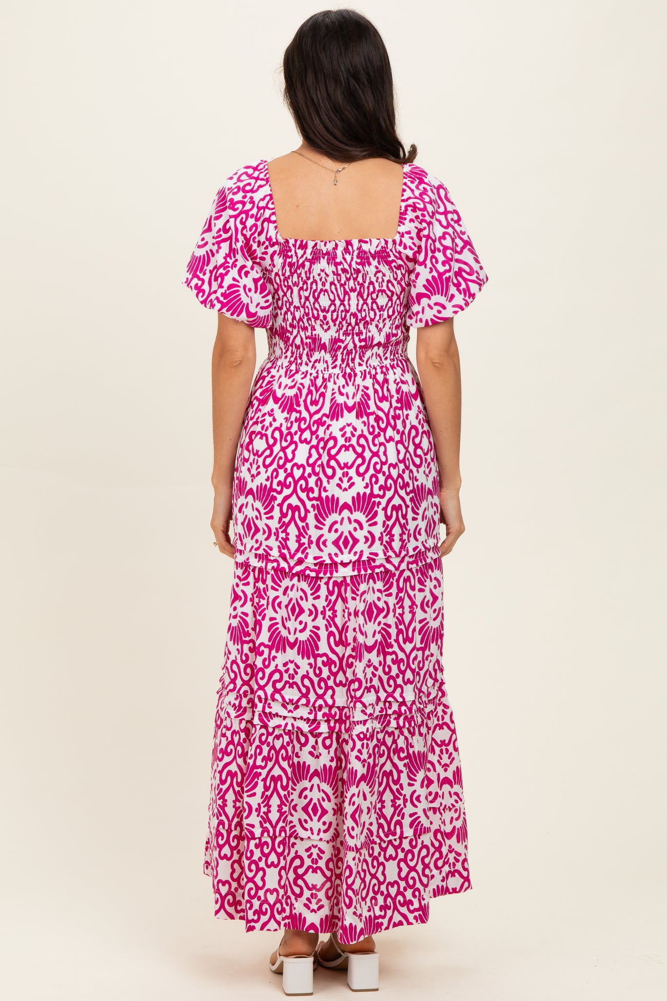 woman wearing a pink floral maxi dress with smocked bodice and tiered skirt, seen from the back
