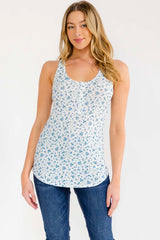 woman wearing a white floral print tank top with a scoop neckline and blue jeans