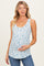 woman wearing a light blue maternity tank top with floral print and holding her baby bump