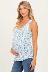 woman wearing a light blue floral maternity tank top and holding her baby bump