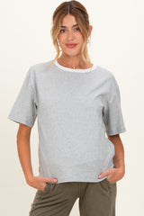 woman wearing a gray short sleeve maternity top with a white neckline and her hands in the pockets