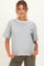 woman wearing a gray short sleeve maternity top with a white neckline and her hands in the pockets