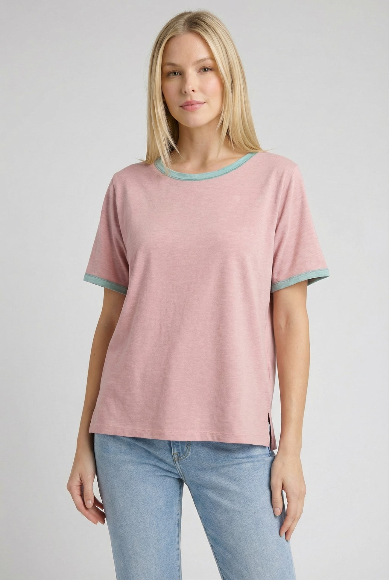 woman wearing a pink short sleeve t-shirt with turquoise trim and side slits, paired with light blue jeans