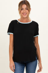 woman wearing a black maternity top with light blue trim and short sleeves, smiling and standing casually