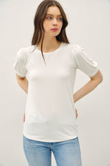 woman wearing a white short sleeve top with puffed sleeves and styled with light blue jeans