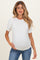 woman wearing a white maternity top with puff sleeves and a visible baby bump, paired with denim jeans