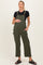 woman wearing a dark green maternity jumpsuit with adjustable straps and pockets, holding her baby bump