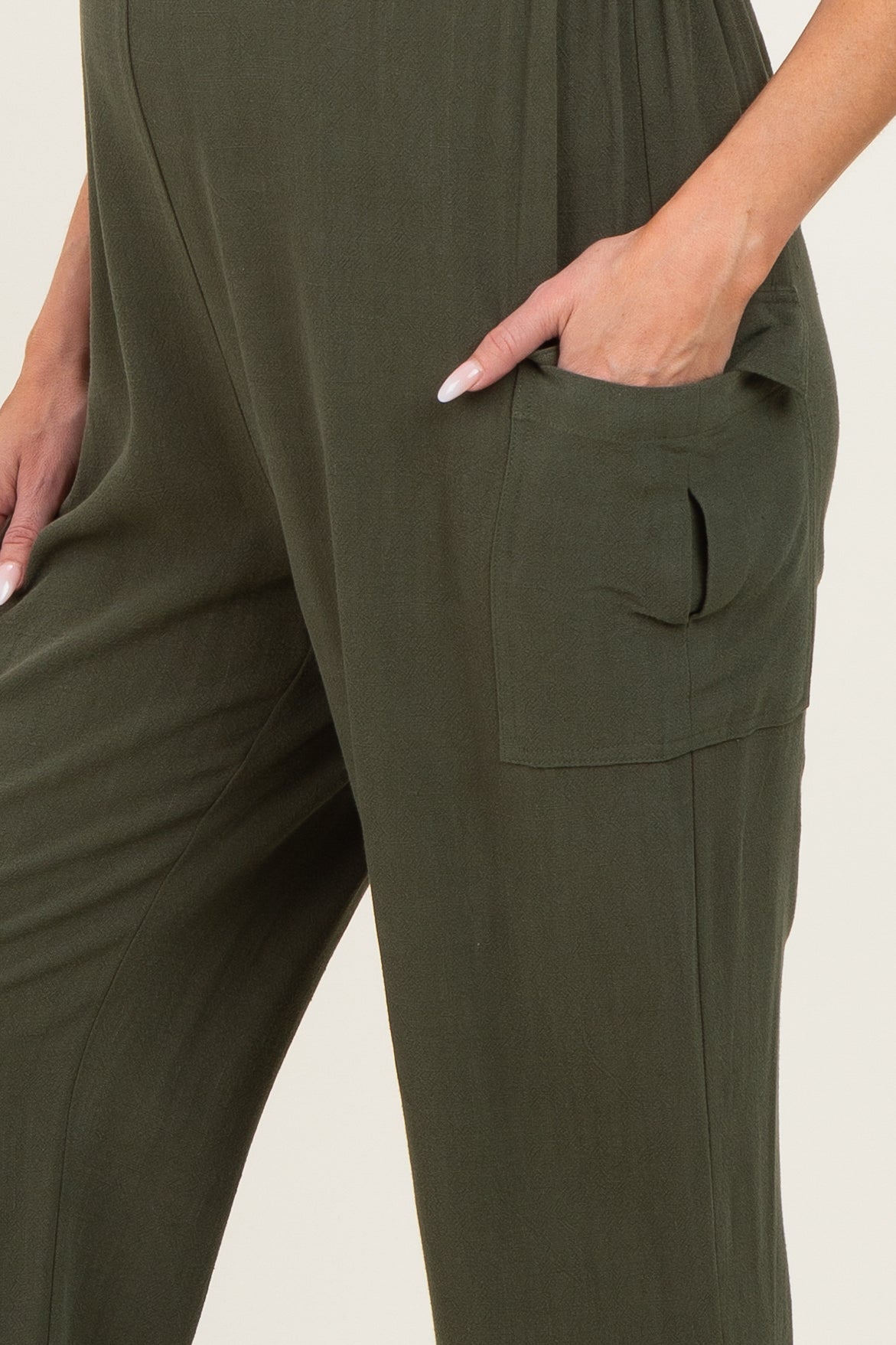 maternity wear olive green jumpsuit featuring a pocket and relaxed fit, model's hand resting on the pocket