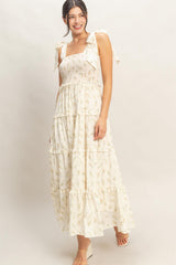 woman wearing a cream floral print maxi dress with tiered ruffles and bow tie straps