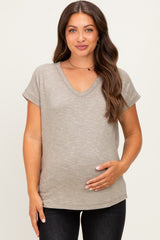 woman wearing a beige short sleeve v-neck maternity top and holding her baby bump