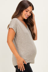 woman wearing a light gray maternity top with a v-neckline and rolled sleeves, showing her baby bump