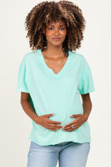 woman wearing a mint green v-neck maternity t-shirt and holding her baby bump