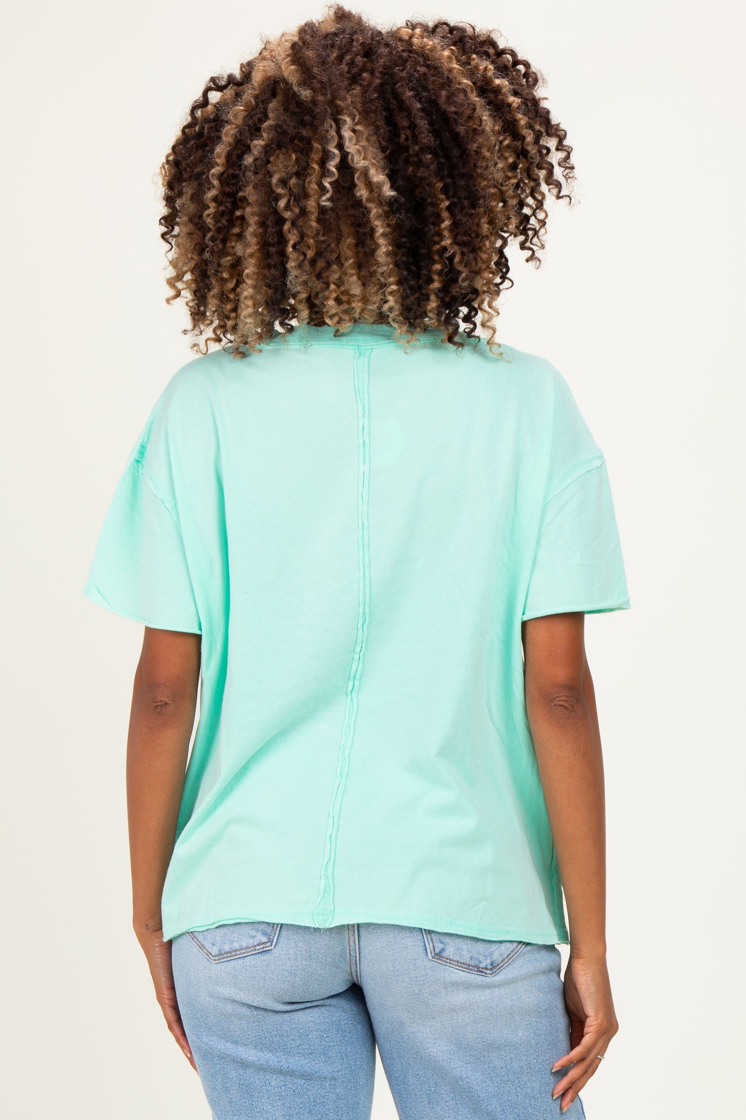 woman wearing a mint green short sleeve maternity top with a relaxed fit and back seam detail