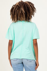 woman wearing a mint green short sleeve maternity top with a relaxed fit and back seam detail