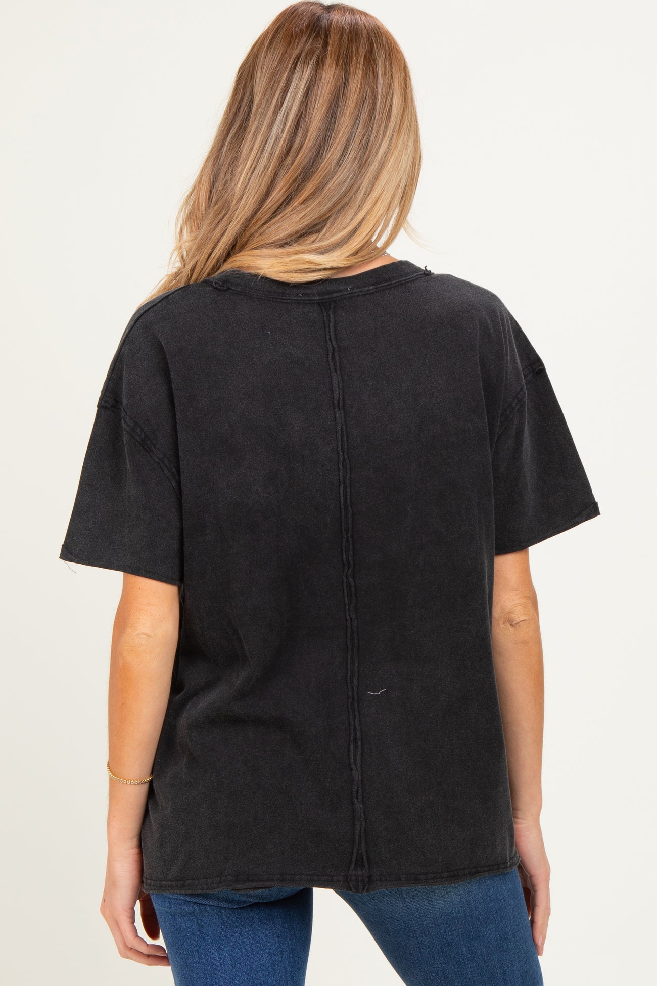woman wearing a black oversized maternity t-shirt, showing the back style with a relaxed fit and stitched detail