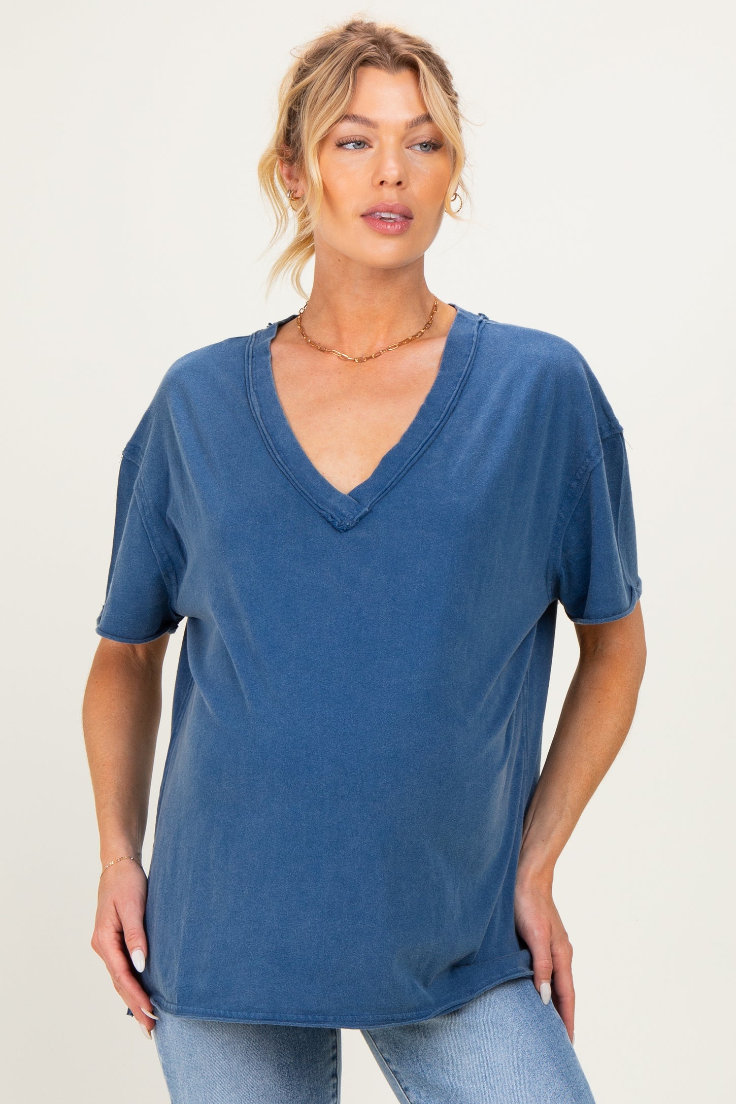woman wearing a blue v-neck maternity tee with rolled short sleeves and a relaxed fit, revealing her baby bump