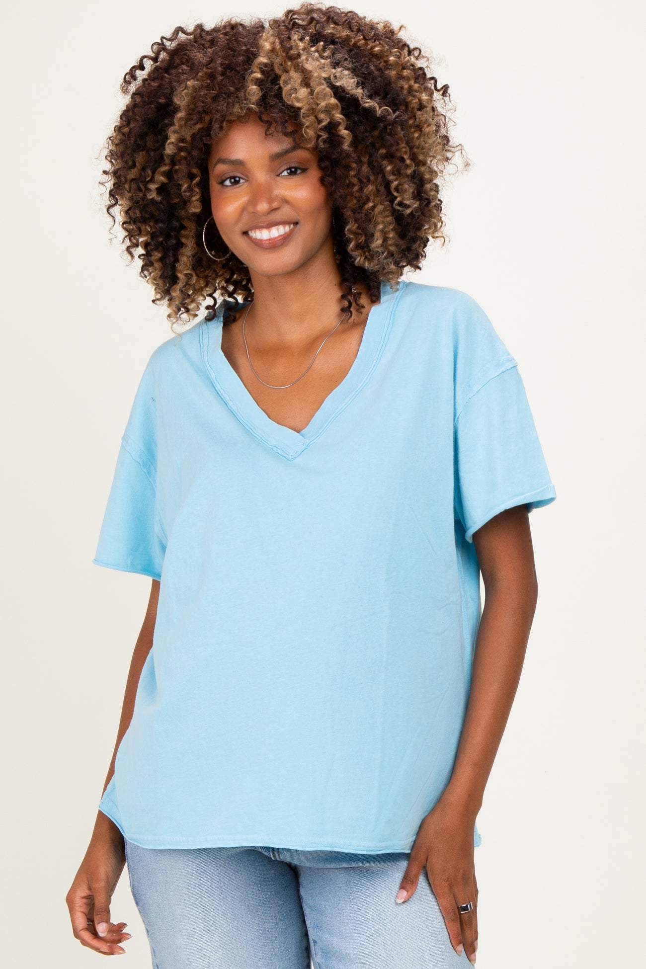 woman wearing a light blue v-neck maternity top with short sleeves and a relaxed fit