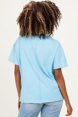 woman wearing a light blue maternity t-shirt with short sleeves and a relaxed fit, showing a back seam detail