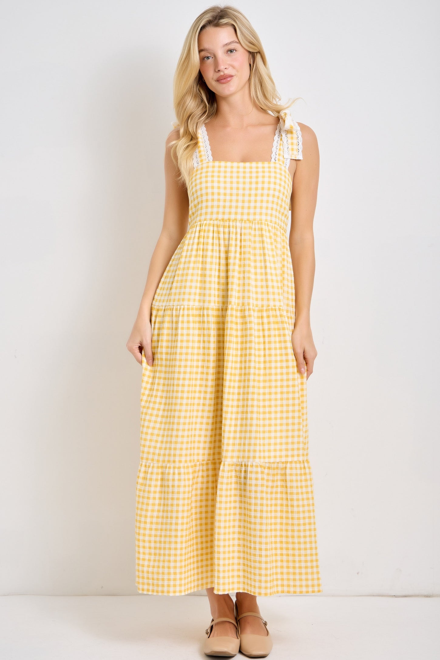 woman wearing a yellow gingham maxi sundress with ruffled straps and a tiered hem