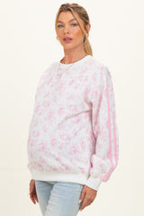 woman wearing a pink floral maternity sweatshirt with white stripes and a visible baby bump