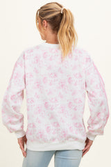 woman wearing a floral print maternity sweatshirt in light pink with puffed sleeves and a relaxed fit