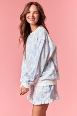 woman wearing a light blue floral print oversized sweatshirt and matching shorts with ruffle hem