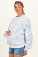woman wearing a light blue floral maternity sweatshirt and showcasing her baby bump with casual denim shorts