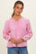 woman wearing a pink long sleeve top with a v-neck and contrast stitching