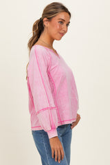 woman wearing a pink long sleeve top with balloon sleeves and a v-neck, standing with hand on her hip