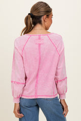 woman wearing a pink long sleeve top with contrast stitching and a relaxed fit, shown from the back