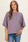 woman wearing a purple and brown striped maternity top and holding her baby bump