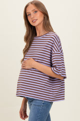woman wearing a purple and brown striped loose-fitting maternity top and holding her baby bump