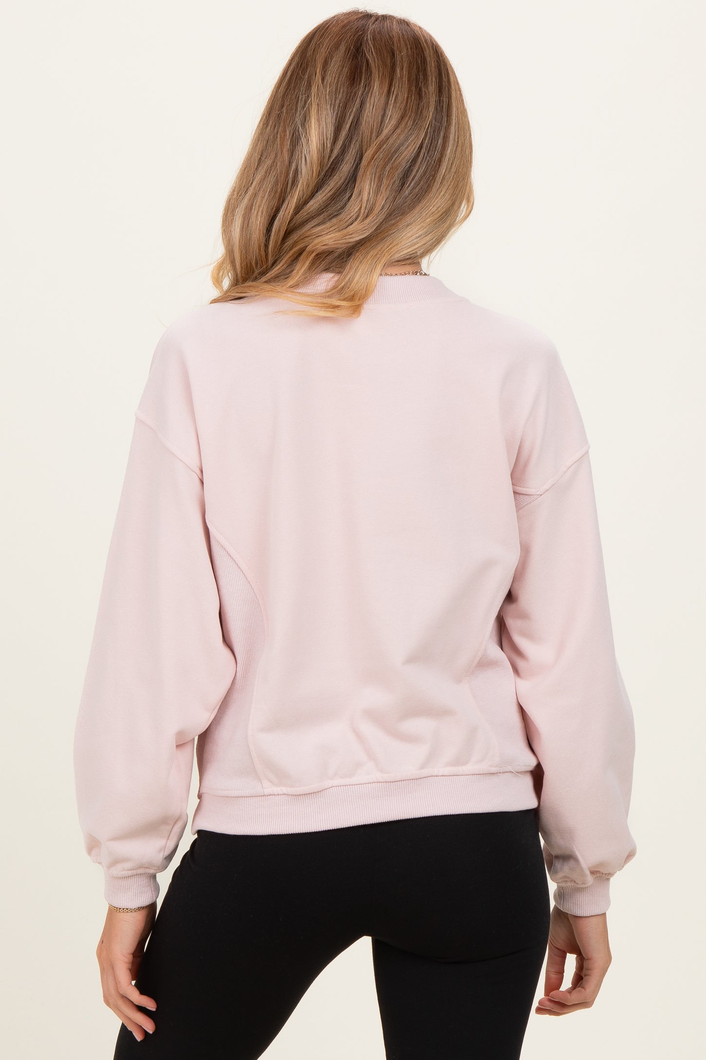 woman wearing a light pink maternity sweatshirt with a relaxed fit and balloon sleeves, seen from the back
