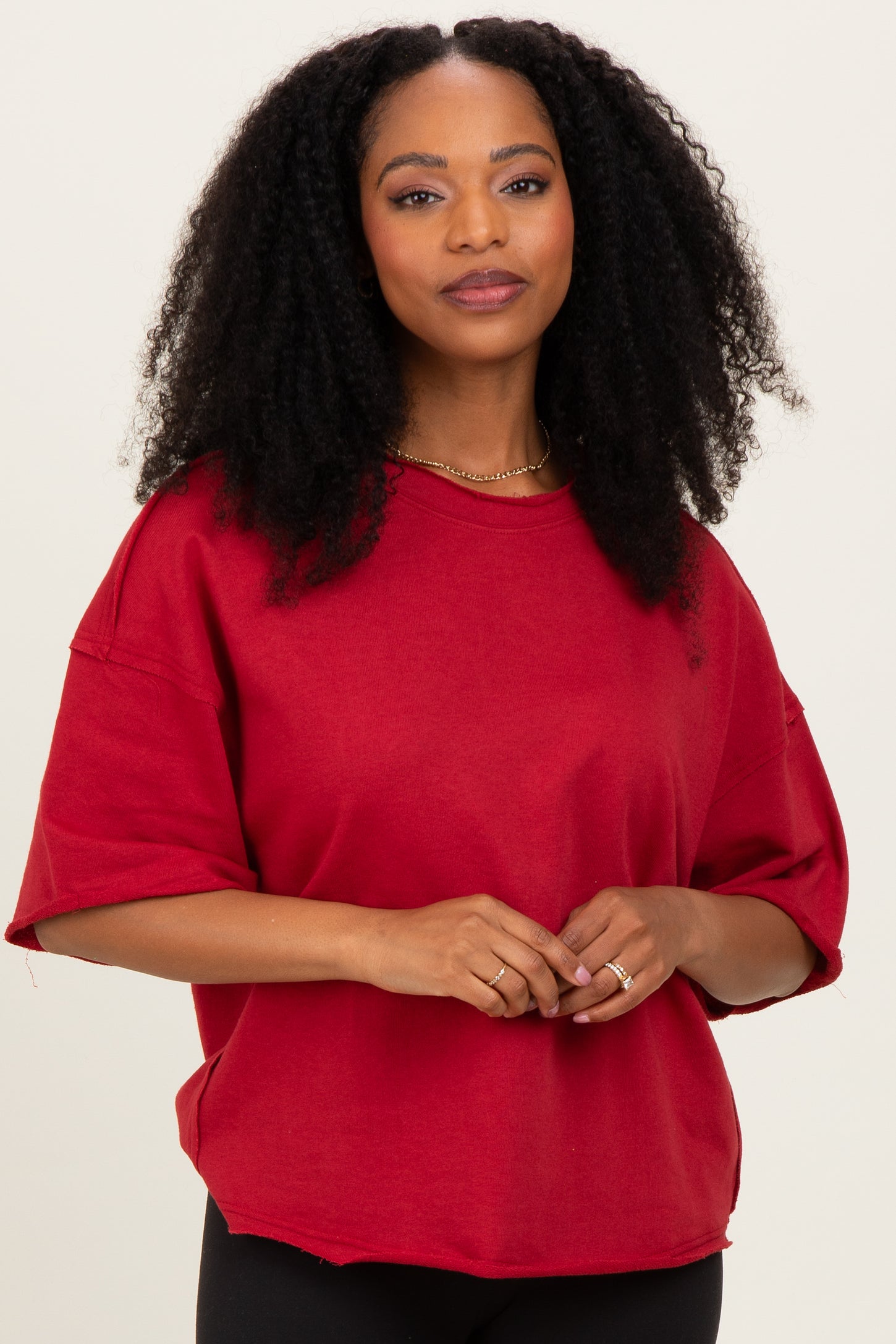 woman wearing a red oversized short sleeve sweatshirt with a relaxed fit and round neckline