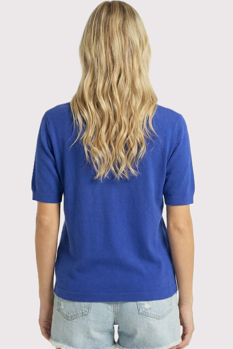 woman wearing a royal blue short sleeve sweater with a relaxed fit and styled with denim shorts