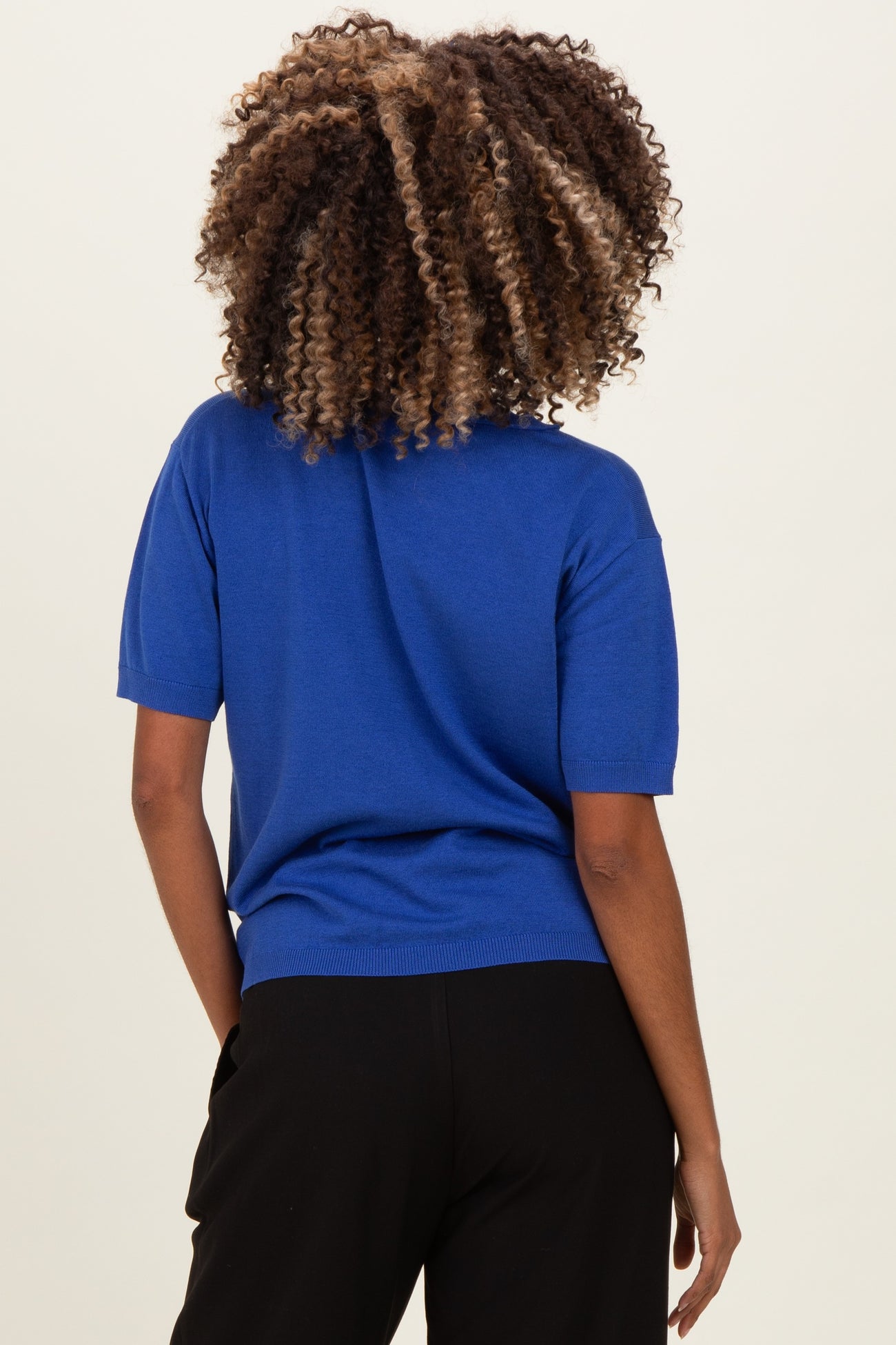 woman wearing a blue short sleeve maternity top, view from the back, showing stylish knit detail