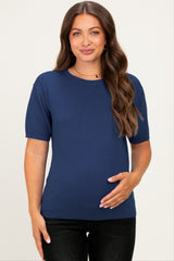 woman wearing a navy short sleeve maternity top and holding her baby bump