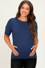 woman wearing a navy blue short sleeve maternity top and holding her baby bump