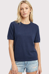 woman wearing a navy blue short sleeve knit top paired with light denim shorts