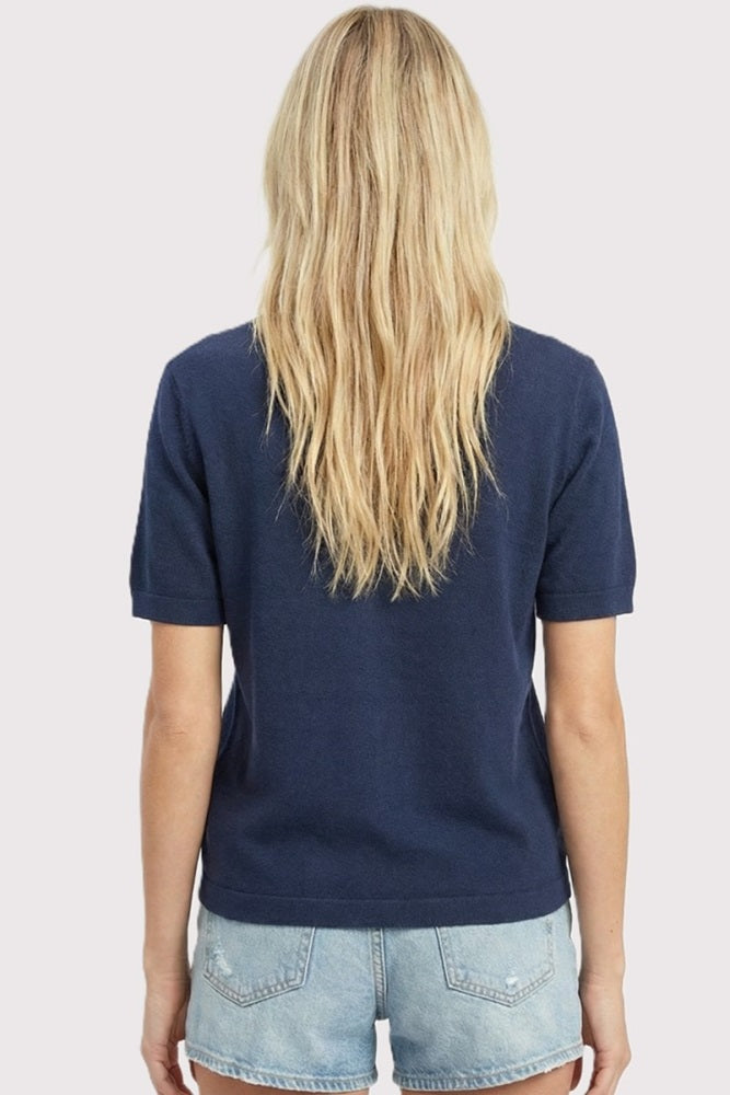 woman wearing a navy short sleeve top with a relaxed fit and denim shorts, viewed from the back