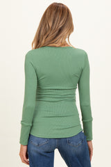 woman wearing a ribbed green long sleeve maternity top, seen from the back with jeans